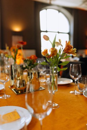 Téléchargez les photos : Couverts, serviettes, assiettes, fleurs sur une table orange. Mise en table. Décor de table orange. anniversaire, mariage dans un restaurant - en image libre de droit