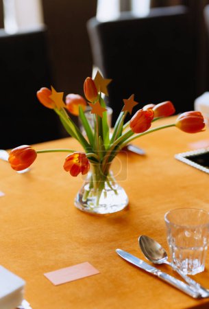 Téléchargez les photos : Tulipes orange sur une table décorée avec une nappe orange. décor lumineux. décor de table pour l'anniversaire d'un enfant - en image libre de droit