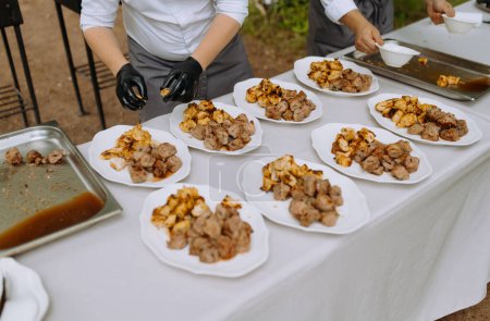 Foto de El chef pone kebabs hechos de pollo, cerdo, carne de ternera en platos. - Imagen libre de derechos
