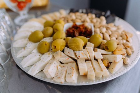 Téléchargez les photos : Vue rapprochée d'une assiette avec fromage, pistaches, olives - en image libre de droit