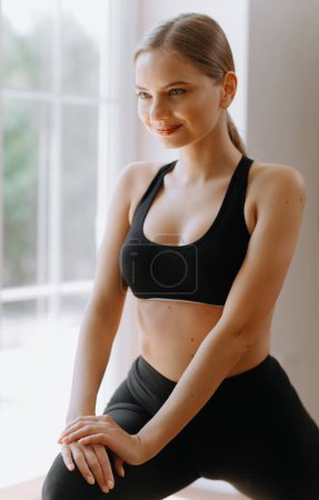 Profile portrait of young attractive yogi woman breathing fresh air, her eyes closed, meditation pose, relaxation exercise, working out wearing black sportswear top, close up image