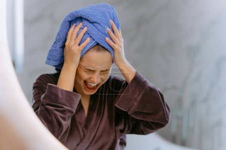 Joven hermosa mujer gritando y usando toalla de ducha después del baño. Chica loca y asustada cogida de la mano en la cabeza, asustada y sorprendida con shock. Grito y decepción de la chica en el baño