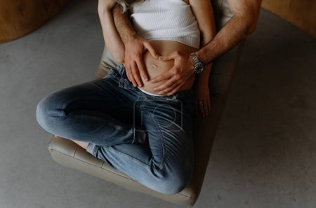 Foto de Una pareja haciendo una forma de corazón en el vientre embarazada con sus manos. Concepto de embarazo, esperando un bebé, cuidado. - Imagen libre de derechos