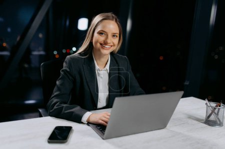 Portrait d'une jeune femme d'affaires assise à son bureau à l'aide d'un ordinateur portable, travaillant au bureau