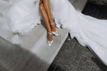 Chaussures blanches de mariage sur les pieds de la mariée. Gros plan. pieds de la mariée au mariage. chaussure, robe, vue sur le dessus