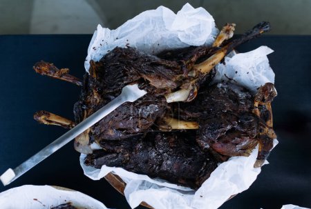 Photo for Burnt bird carcass on the tablecloth on the dining table. Serve a burnt spoiled dish. Bake the meat in the oven. Terrible dish. - Royalty Free Image