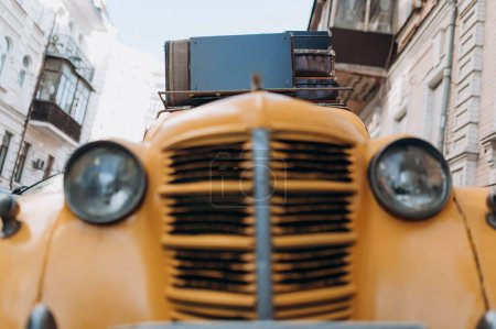 Téléchargez les photos : Yellow retro taxi with luggage on the roof. A yellow vintage taxi car. Car front view - en image libre de droit