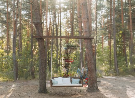 Wooden summer swing in a pine forest. Summer vacation in the country.