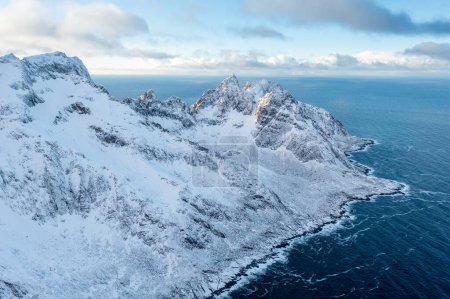 Photo for Snow covered mountain range on coastline in winter, Norway. Senja panoramic aerial view landscape nordic snow cold winter norway ocean cloudy sky snowy mountains. Troms county, Fjordgard - Royalty Free Image
