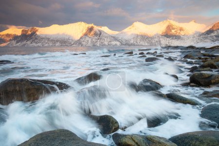 Téléchargez les photos : Chaîne de montagnes enneigée sur le littoral en hiver, Norvège. Senja panoramique vue aérienne paysage neige nordique froid hiver nordique océan ciel nuageux montagnes enneigées. Comté de Troms, Fjordgard - en image libre de droit
