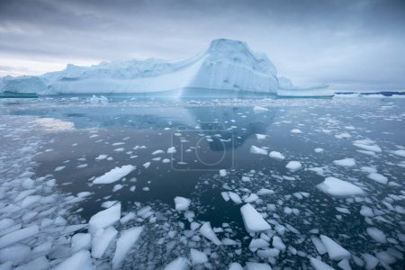Foto de El derretimiento de un iceberg y el vertido de agua en el mar por la costa de Groenlandia Groenlandia y el increíble iceberg en el mar, todavía podemos ver esto antes de completar el cambio climático. Icefjord Calentamiento global. - Imagen libre de derechos