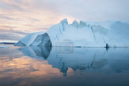 Téléchargez les photos : Des icebergs au coucher du soleil. Nature et paysages du Groenland. Disko bay. Groenland Ouest. Soleil de minuit d'été et icebergs. Grosse glace bleue dans le glacier. Affecté par le changement climatique et le réchauffement climatique - en image libre de droit