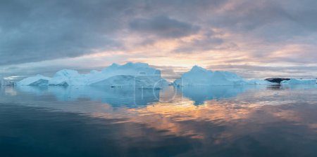 Téléchargez les photos : Des icebergs au coucher du soleil. Nature et paysages du Groenland. Disko bay. Groenland Ouest. Soleil de minuit d'été et icebergs. Grosse glace bleue dans le glacier. Affecté par le changement climatique et le réchauffement climatique - en image libre de droit