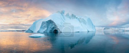 Foto de Paisaje de la naturaleza ártica con témpanos en la Antártida con la salida del sol de medianoche en el horizonte. Sol de medianoche de verano y témpanos. Gran hielo azul en el fiordo de hielo. Cambio climático calentamiento global. - Imagen libre de derechos