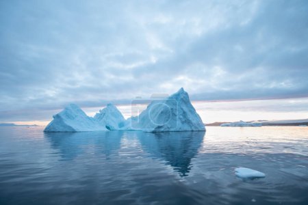 Photo for Arctic nature landscape with icebergs in Antarctica with midnight sun sunset sunrise in the horizon. Summer Midnight Sun and icebergs. Big blue ice in icefjord. Climate change global warming. - Royalty Free Image