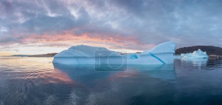 Foto de Paisaje de la naturaleza ártica con témpanos en la Antártida con la salida del sol de medianoche en el horizonte. Sol de medianoche de verano y témpanos. Gran hielo azul en el fiordo de hielo. Cambio climático calentamiento global. - Imagen libre de derechos