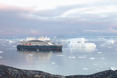 Téléchargez les photos : Le navire de croisière d'expédition à l'ancre près du port d'Ilulissat dans le sud du Groenland. Il navigue à travers les icebergs. Climat de réchauffement climatique. Changer la fonte des glaces - en image libre de droit