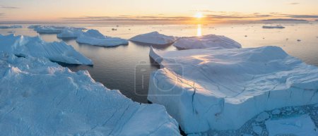 Photo for Arctic nature landscape with icebergs in Antarctica with midnight sun sunset sunrise in the horizon. Summer Midnight Sun and icebergs. Big blue ice in icefjord. Climate change global warming. - Royalty Free Image