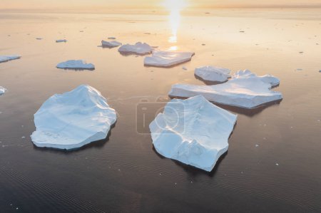 Téléchargez les photos : Fondre des icebergs sur la côte du Groenland, par une belle journée d'été - Fondre des icebergs et verser de l'eau dans la mer. Réchauffement climatique Arctique nature paysage, Journée d'été - en image libre de droit