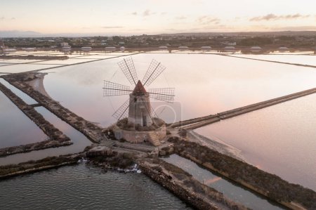 Photo for Sunset at Windmill in the salt evaporation pond in Marsala, Sicily island, Italy Trapani salt flats and old windmill in Sicily. View in beautiful sunny day. - Royalty Free Image