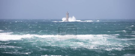 Téléchargez les photos : Phare appelé "Le phare du four" à Tremazan en Bretagne, France lors d'une tempête en hiver. Grandes vagues brisées près du littoral de pierre de France et du phare. - en image libre de droit