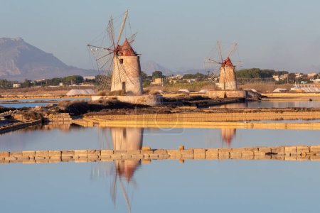 Photo for Sunset at Windmills in the salt evaporation pond in Marsala, Sicily island, Italy Trapani salt flats and old windmill in Sicily. View in beautiful sunny day. - Royalty Free Image