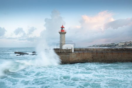 Photo for Beautiful sunset on the old pier and The Felgueiras Lighthouse at the mouth of the river Douro, Porto, Portugal Big breaking sea wave splash at sunset. - Royalty Free Image
