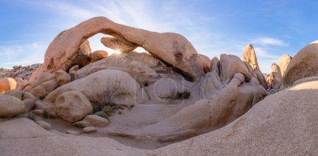 Téléchargez les photos : Amazing Arch rock à l'intérieur du parc national Joshua Tree. Impressionnante formation de pierre et de roche avec un ciel bleu en arrière-plan. Emplacement touristique sud de la Californie pendant l'été chaud. Désert au lever du soleil - en image libre de droit