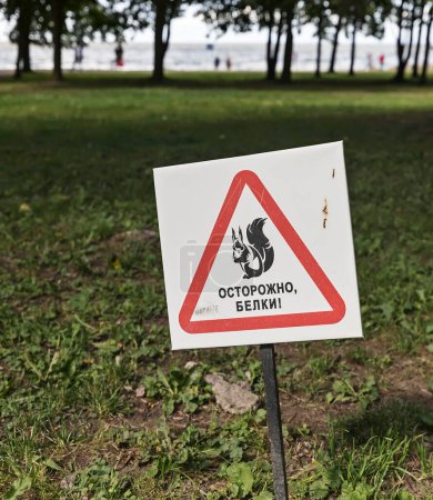 A sign with an image of a squirrel in red triangle and the inscription in Cyrillic, saying "Beware of squirrels" in a park near St. Petersburg, Russia.