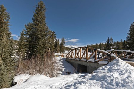 Bridge across Fraser river, covered in snow, at the Winter Park Ski resort, Colorado, USA.
