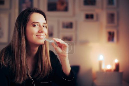 Photo for Smiling Woman Using an Orthodontic Transparent Silicone Teeth aligner at Night - Royalty Free Image
