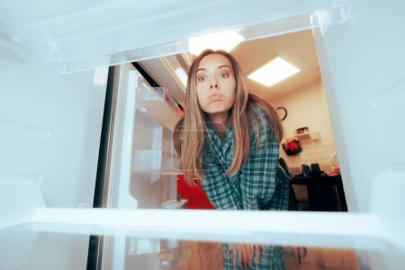Photo for Confused Girl Looking into Her Empty Refrigerator - Royalty Free Image
