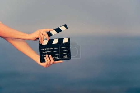 Mano sosteniendo una película de cine pizarra en la playa junto al mar