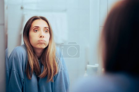 Unglückliche Frau blickt in den Spiegel und fühlt sich überwältigt 