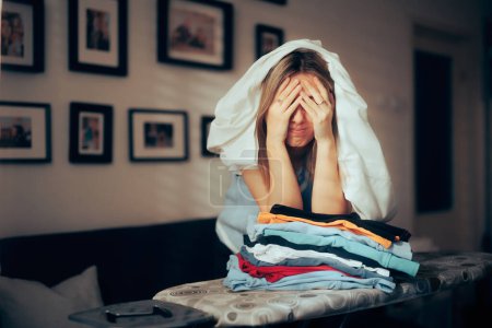 Téléchargez les photos : Stressé femme désespérée ayant à repasser une pile de blanchisserie - en image libre de droit
