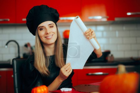 Téléchargez les photos : Happy Woman utilisant du papier cuisson dans la cuisine - en image libre de droit
