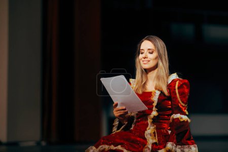 Foto de Hermosa actriz leyendo sus líneas sentado en el escenario - Imagen libre de derechos