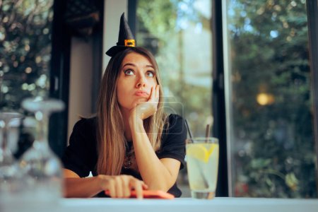 Traurige Frau mit Halloween-Hexenhut wartet allein auf Party