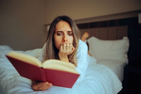 Photo for Focused Woman Reading a Captivating Book in Bed - Royalty Free Image
