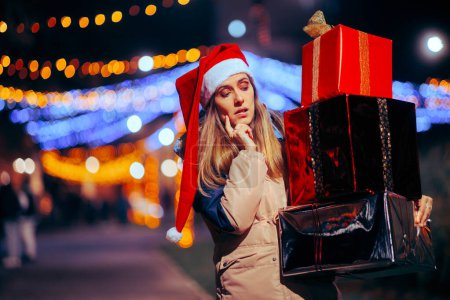 Mujer de Navidad desconcertada sosteniendo una gran pila de cajas de regalo