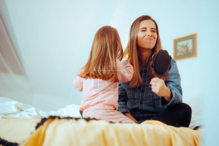 Photo for Daughter Pulls Mom Hair When She tries to Comb her Funny family having fun in a role play activity - Royalty Free Image