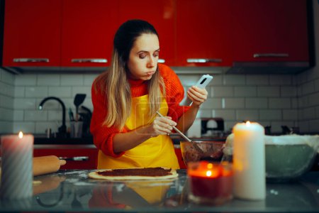 Téléchargez les photos : Femme suivant tutoriel en ligne tout en cuisinant à la maison - en image libre de droit