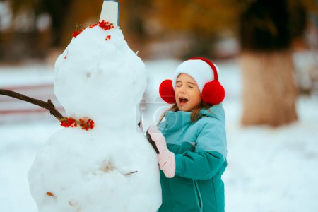 Téléchargez les photos : Joyeux petite fille profiter de l'hiver Construire un bonhomme de neige - en image libre de droit