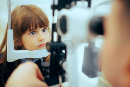 Téléchargez les photos : Petite fille pendant l'examen des yeux avec un microscope à lampe à fente. - en image libre de droit