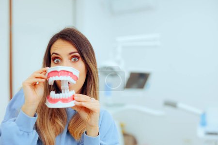 Lustige Frau mit Zahnmodell in Zahnarztpraxis
