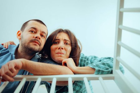 Worried Parents Looking into the Crib Having Mixed Feelings