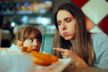 Photo for Mom Pointing to her Little Girl Eating Unhealthy Foods - Royalty Free Image