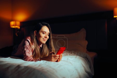 Happy Woman Checking her Phone at Home in Bed