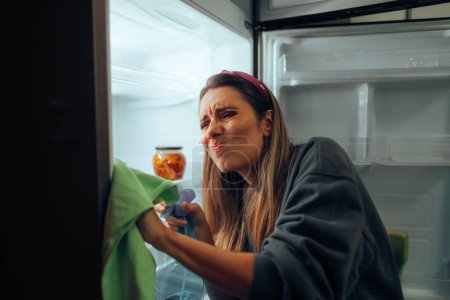 Woman Cleaning her Refrigerator Using a Special Detergent Solution