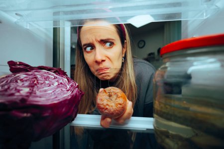 Frau holt faules Obst aus ihrem Kühlschrank 